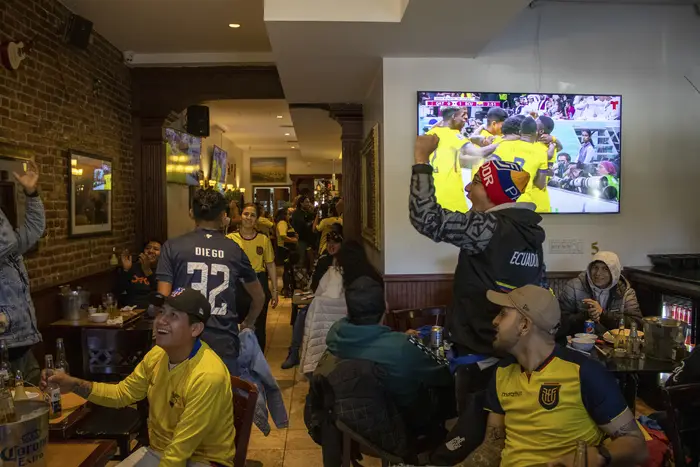 Fans of the Ecuadorian soccer team celebrate in a bar.